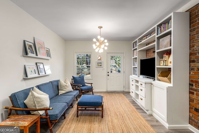 living area with an inviting chandelier, light wood-style flooring, and baseboards