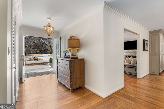 hallway featuring ornamental molding, light wood-type flooring, and an inviting chandelier