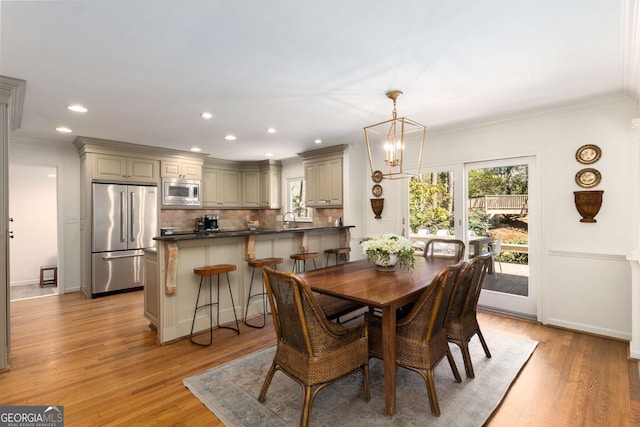 dining area featuring light wood finished floors, ornamental molding, a chandelier, and recessed lighting