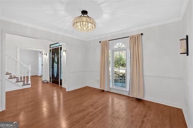 interior space with a notable chandelier, crown molding, wood finished floors, baseboards, and stairs