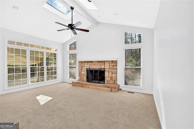 unfurnished living room featuring a wealth of natural light, a skylight, beam ceiling, and a stone fireplace