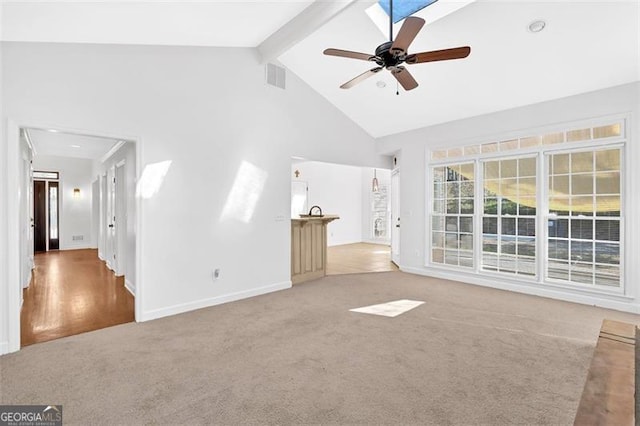 unfurnished living room featuring high vaulted ceiling, carpet, beam ceiling, visible vents, and a ceiling fan