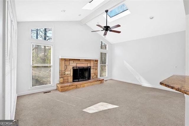 unfurnished living room with a skylight, a fireplace, visible vents, beamed ceiling, and carpet