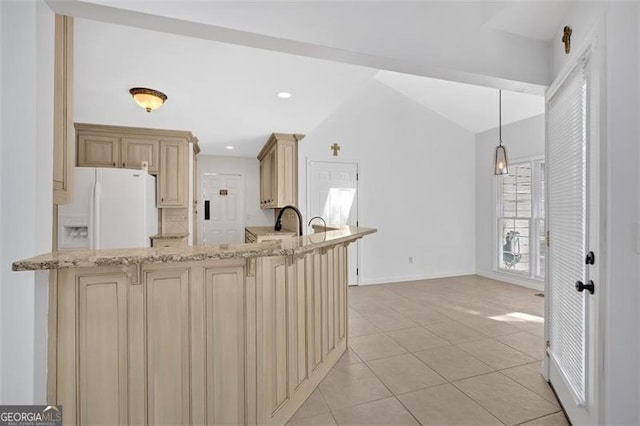 kitchen with light tile patterned flooring, white refrigerator with ice dispenser, light stone countertops, a peninsula, and cream cabinetry