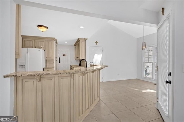 kitchen featuring light stone counters, cream cabinets, vaulted ceiling, white fridge with ice dispenser, and light tile patterned flooring