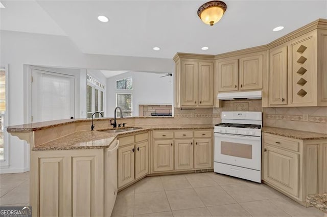 kitchen with white gas stove, tasteful backsplash, cream cabinets, and under cabinet range hood