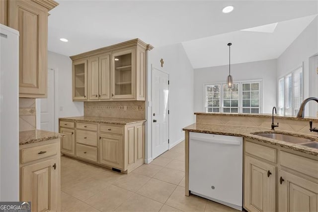 kitchen with decorative backsplash, dishwasher, glass insert cabinets, light stone counters, and a sink