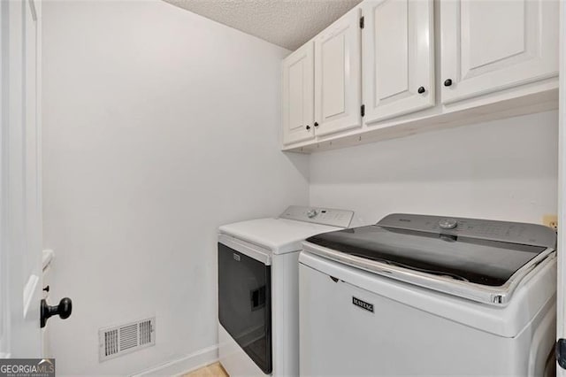 laundry room featuring cabinet space, baseboards, visible vents, washer and clothes dryer, and a textured ceiling