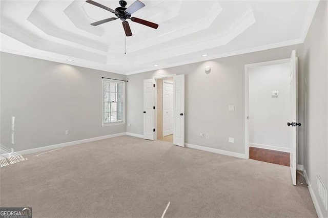 unfurnished bedroom with carpet, a tray ceiling, and baseboards