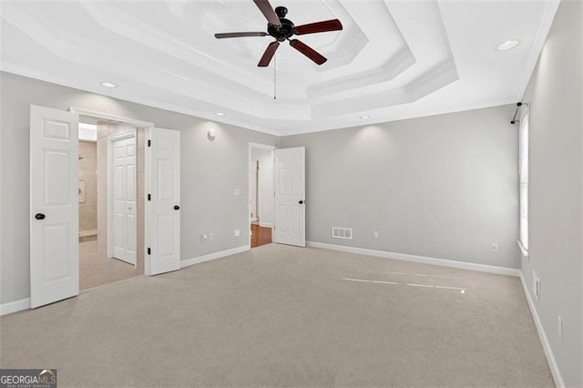 unfurnished bedroom with ornamental molding, a raised ceiling, visible vents, and light colored carpet