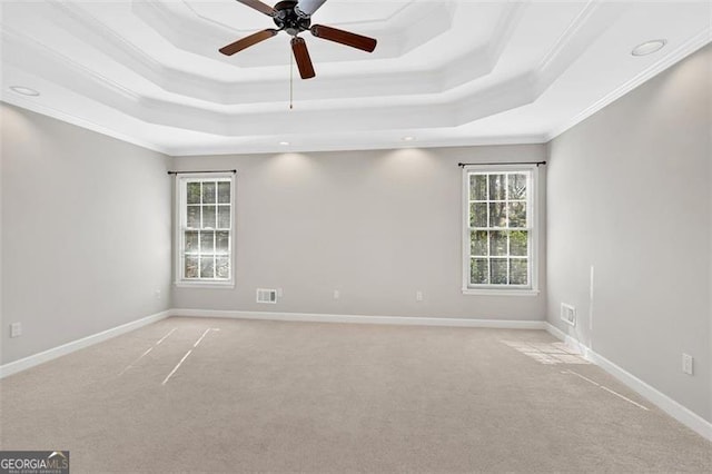 unfurnished room featuring visible vents, a tray ceiling, and baseboards