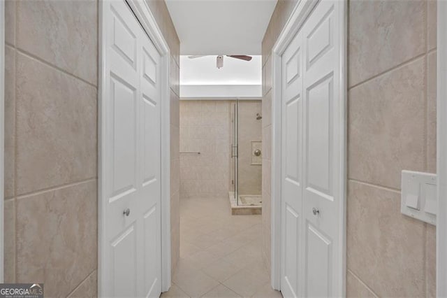 hall featuring light tile patterned flooring and tile walls