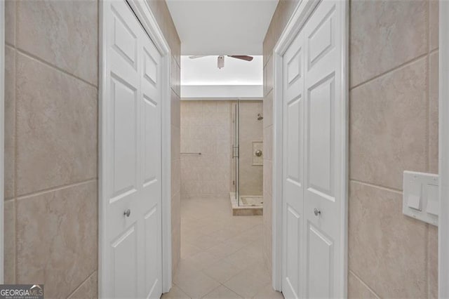 corridor featuring light tile patterned floors and tile walls