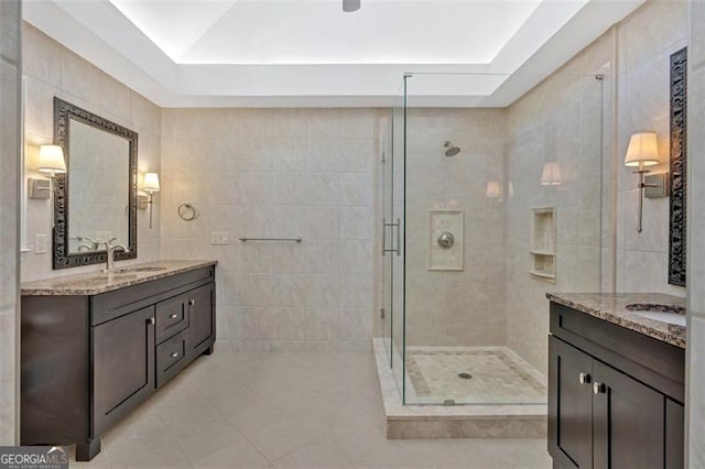 full bath with a stall shower, tile patterned flooring, tile walls, and vanity