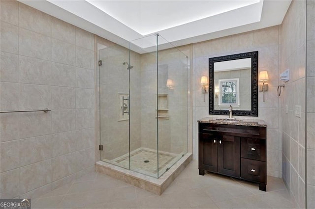 bathroom featuring a stall shower, tile walls, vanity, and tile patterned floors