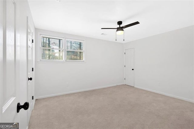 spare room featuring light colored carpet, visible vents, baseboards, and a ceiling fan