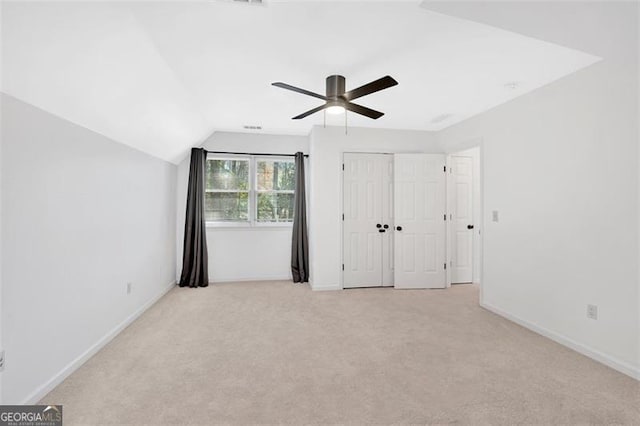 unfurnished bedroom with baseboards, light colored carpet, lofted ceiling, ceiling fan, and a closet