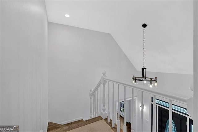 stairway featuring vaulted ceiling and an inviting chandelier