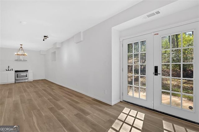 unfurnished living room with french doors, visible vents, a sink, and wood finished floors