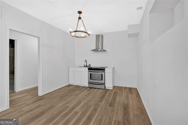 kitchen featuring wood finished floors, wall chimney range hood, electric stove, visible vents, and white cabinets
