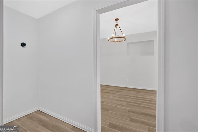 interior space featuring a chandelier, wood finished floors, and baseboards