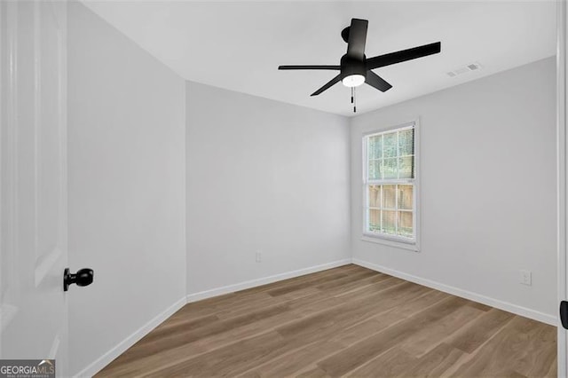 empty room featuring ceiling fan, wood finished floors, visible vents, and baseboards