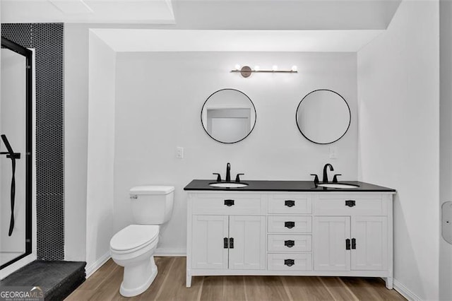full bathroom featuring toilet, a sink, double vanity, and wood finished floors