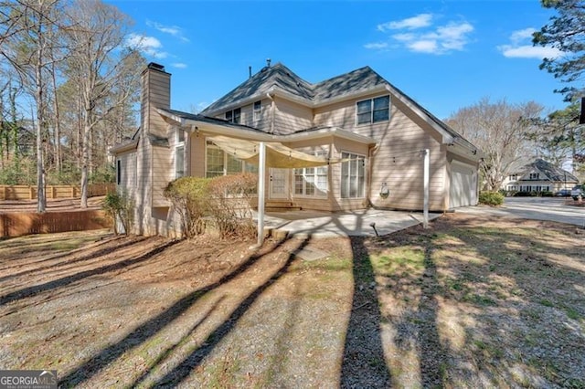 exterior space with an attached garage, fence, driveway, a chimney, and a patio area