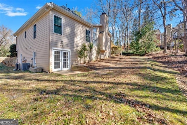 view of home's exterior with a chimney, a lawn, and french doors