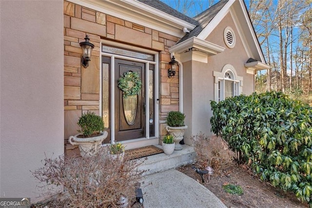 view of exterior entry with stone siding and stucco siding