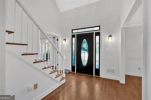 foyer entrance with wood finished floors, baseboards, stairs, and visible vents