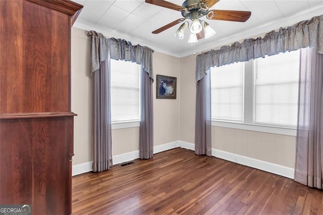 unfurnished room with baseboards, visible vents, a ceiling fan, ornamental molding, and wood finished floors