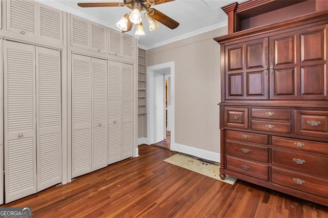 unfurnished bedroom with dark wood-style floors, ceiling fan, baseboards, and crown molding