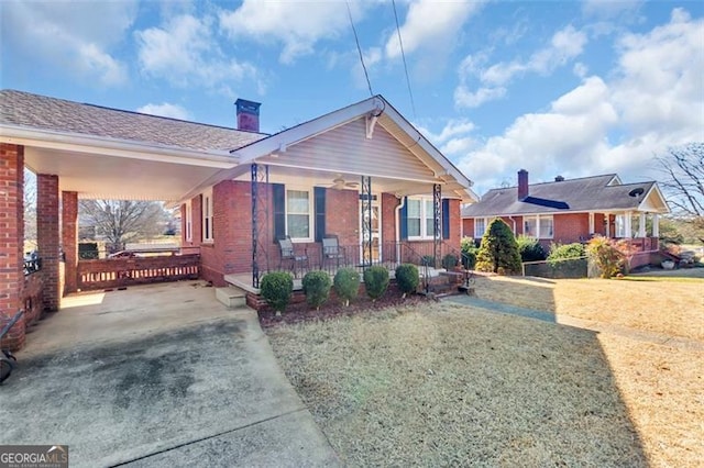 bungalow with covered porch, a front lawn, an attached carport, and brick siding