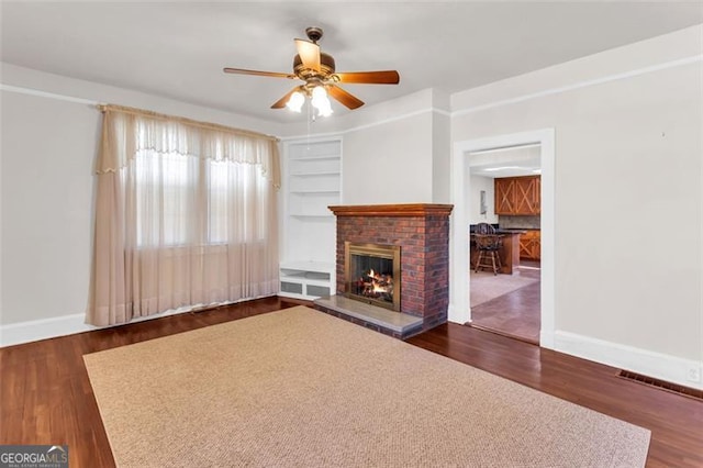 unfurnished living room with a fireplace, baseboards, and dark wood finished floors