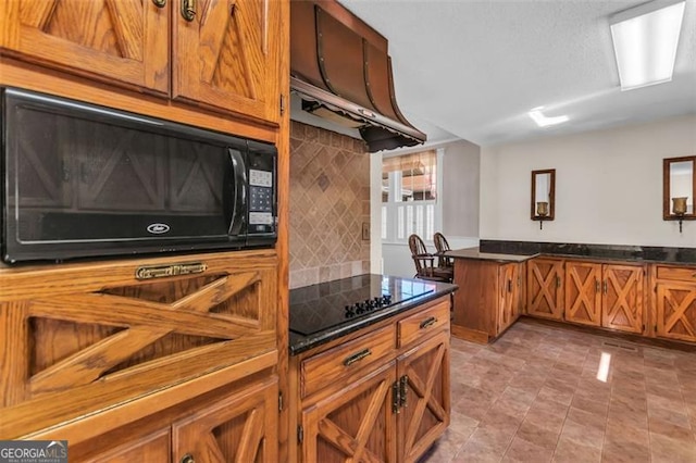 kitchen with light tile patterned flooring, exhaust hood, decorative backsplash, black appliances, and brown cabinetry