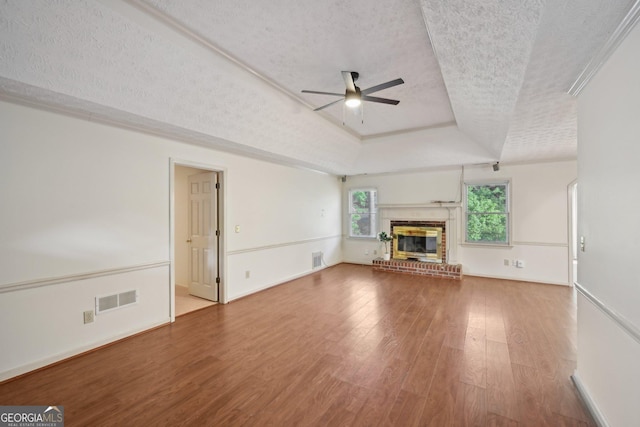 2768 Southpark Blvd SW, Conyers, GA 30094 - unfurnished living room with ceiling fan, a textured ceiling, a tray ceiling, wood finished floors, and a brick fireplace