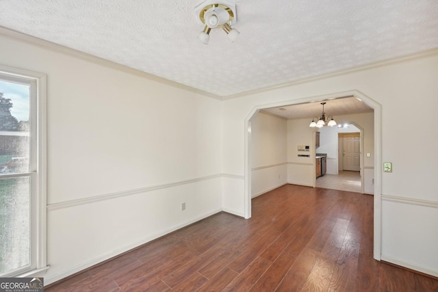 2768 Southpark Blvd SW, Conyers, GA 30094 - empty room featuring arched walkways, dark wood-style floors, a chandelier, a textured ceiling, and ornamental molding