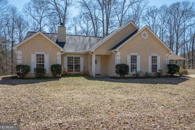 view of front of home with a front yard, a shingled roof, a chimney, and stucco siding