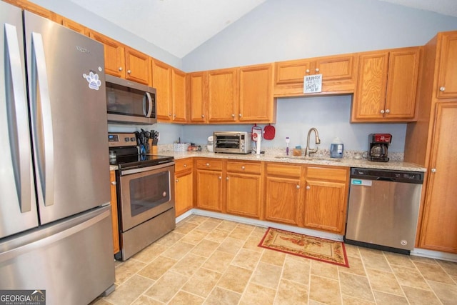 kitchen featuring a toaster, stainless steel appliances, a sink, vaulted ceiling, and light stone countertops