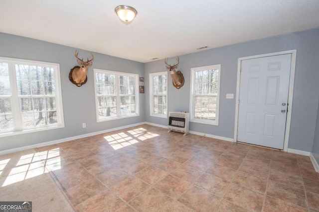 interior space with baseboards, light tile patterned floors, visible vents, and heating unit