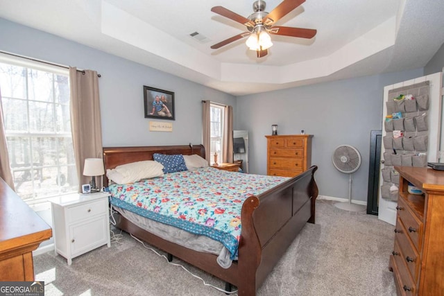 bedroom with light carpet, multiple windows, visible vents, and a raised ceiling