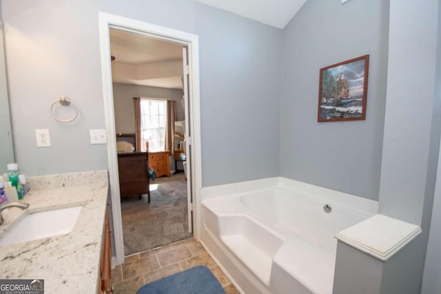 ensuite bathroom with a garden tub, connected bathroom, vanity, and tile patterned floors