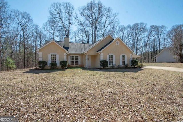 view of front of home with a chimney, a front lawn, and stucco siding