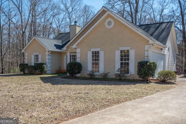 view of front facade featuring a shingled roof, a chimney, an attached garage, and stucco siding