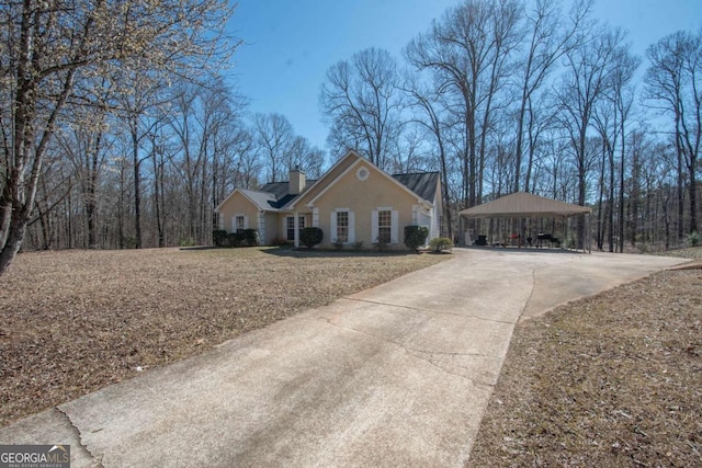 view of front facade featuring concrete driveway and a chimney