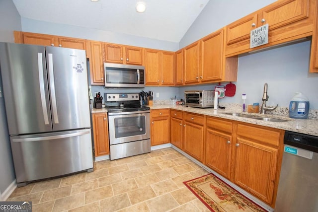 kitchen featuring light stone counters, a toaster, stainless steel appliances, a sink, and vaulted ceiling