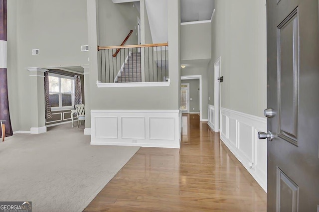 foyer entrance with visible vents, a decorative wall, stairway, and a high ceiling