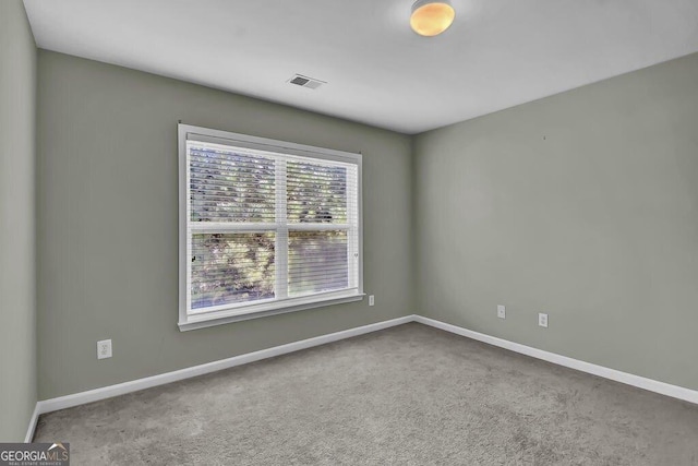 unfurnished room featuring carpet flooring, visible vents, and baseboards