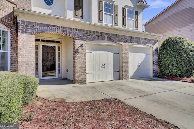 view of exterior entry featuring concrete driveway, brick siding, and an attached garage